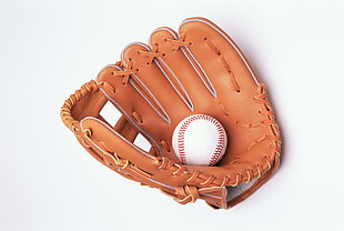 white baseball on brown baseball mitt